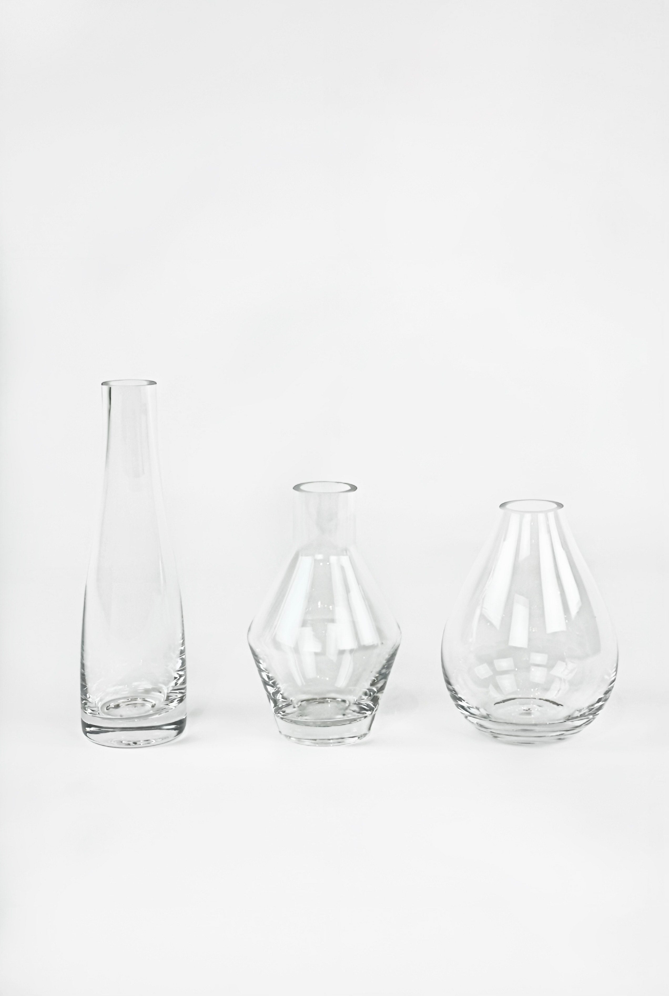 Three clear glass vases of different shapes on a white background