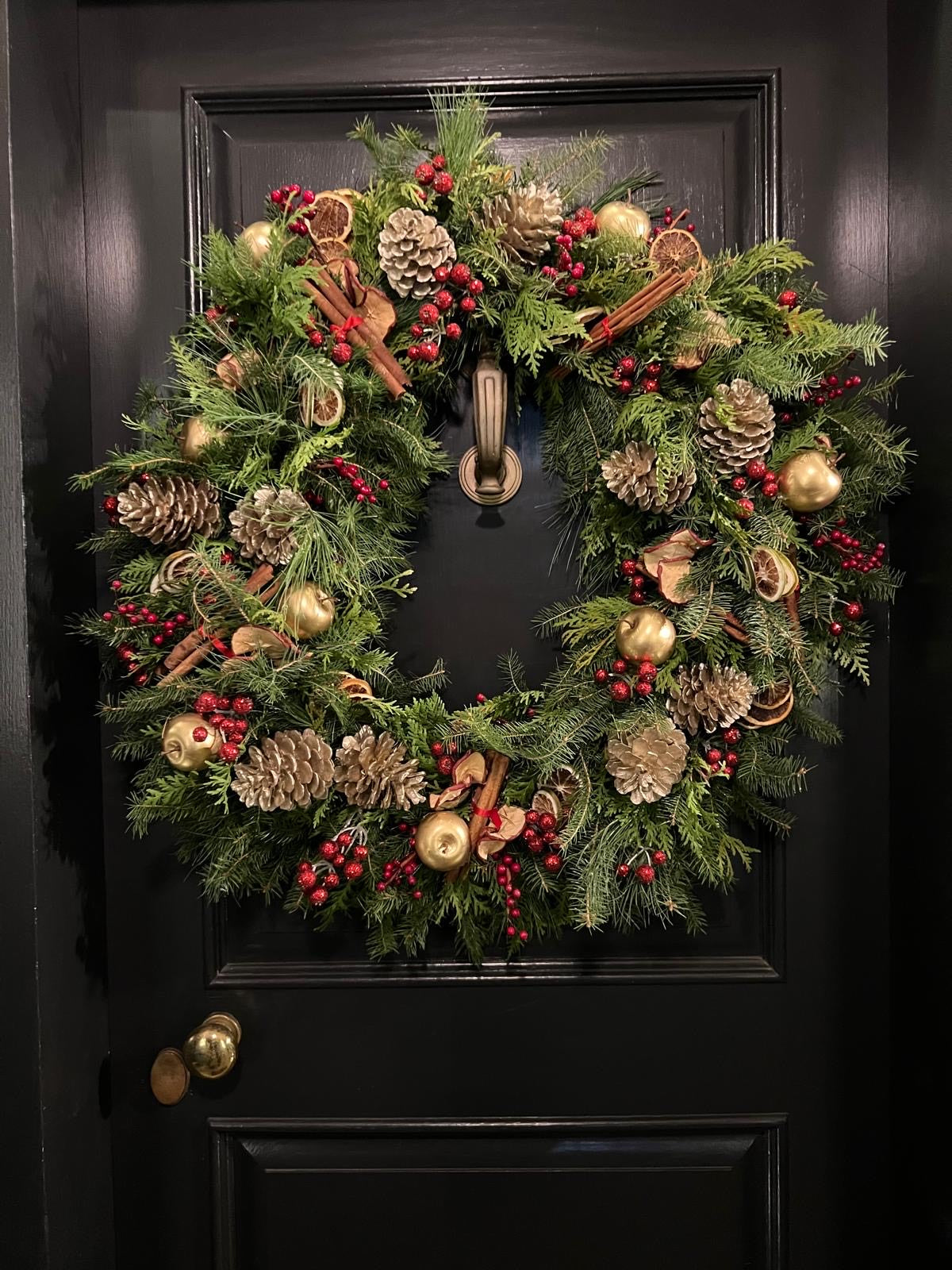 Decorative Christmas wreath on a black door with gold accents